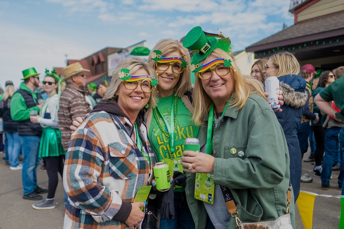 Crosslake-St.-Patricks-Day-three-middle-aged-women-wearing-green-and-smiling-dark.webp
