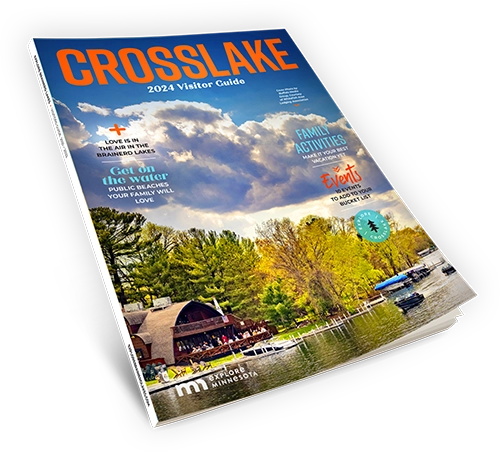 A 2024 Crosslake Visitor Guide magaizne showing the cover with a large photo of lake with boats in it and a resturant at the edge of the shore